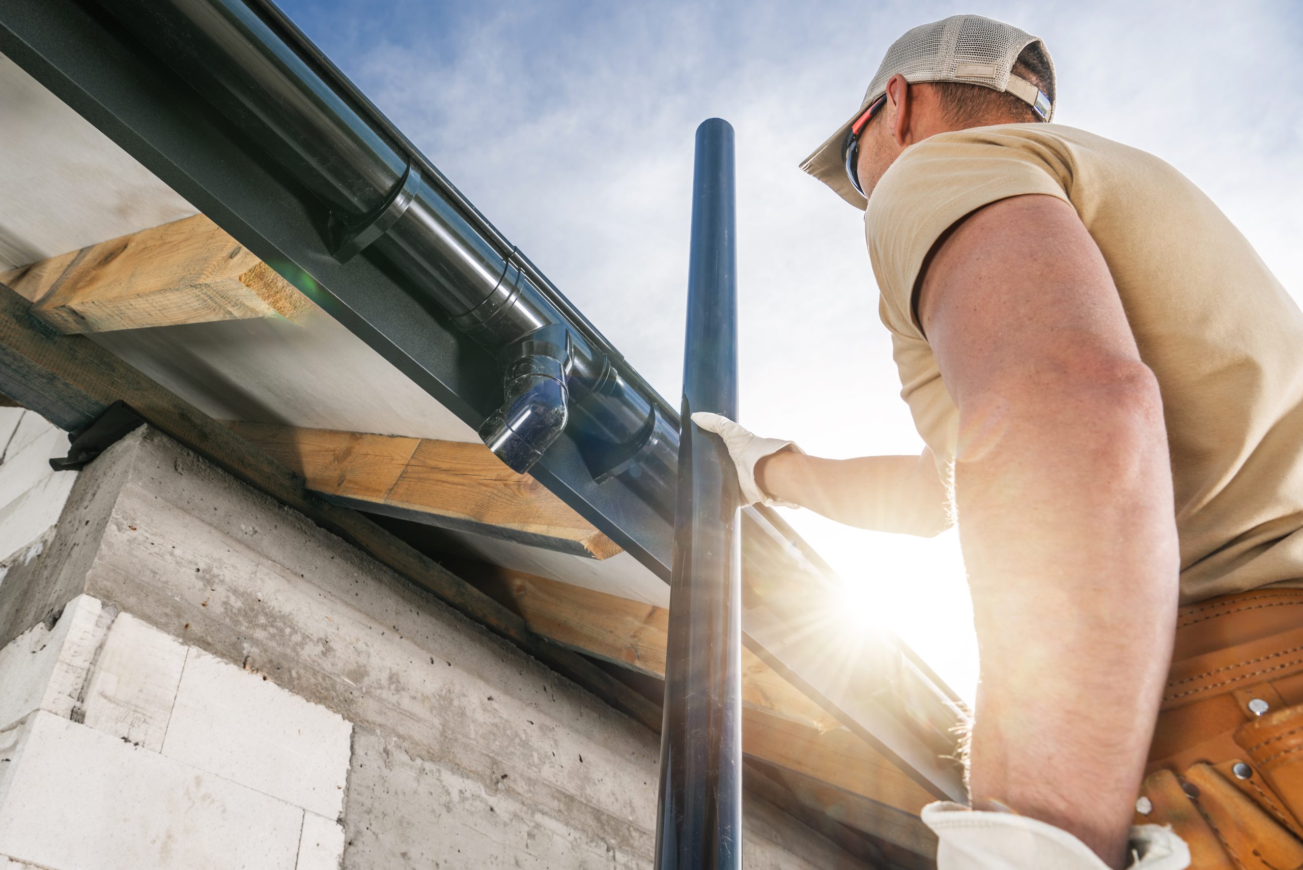 Construction Roof Worker Installing House Gutters in Newly Developed Concrete Bricks House