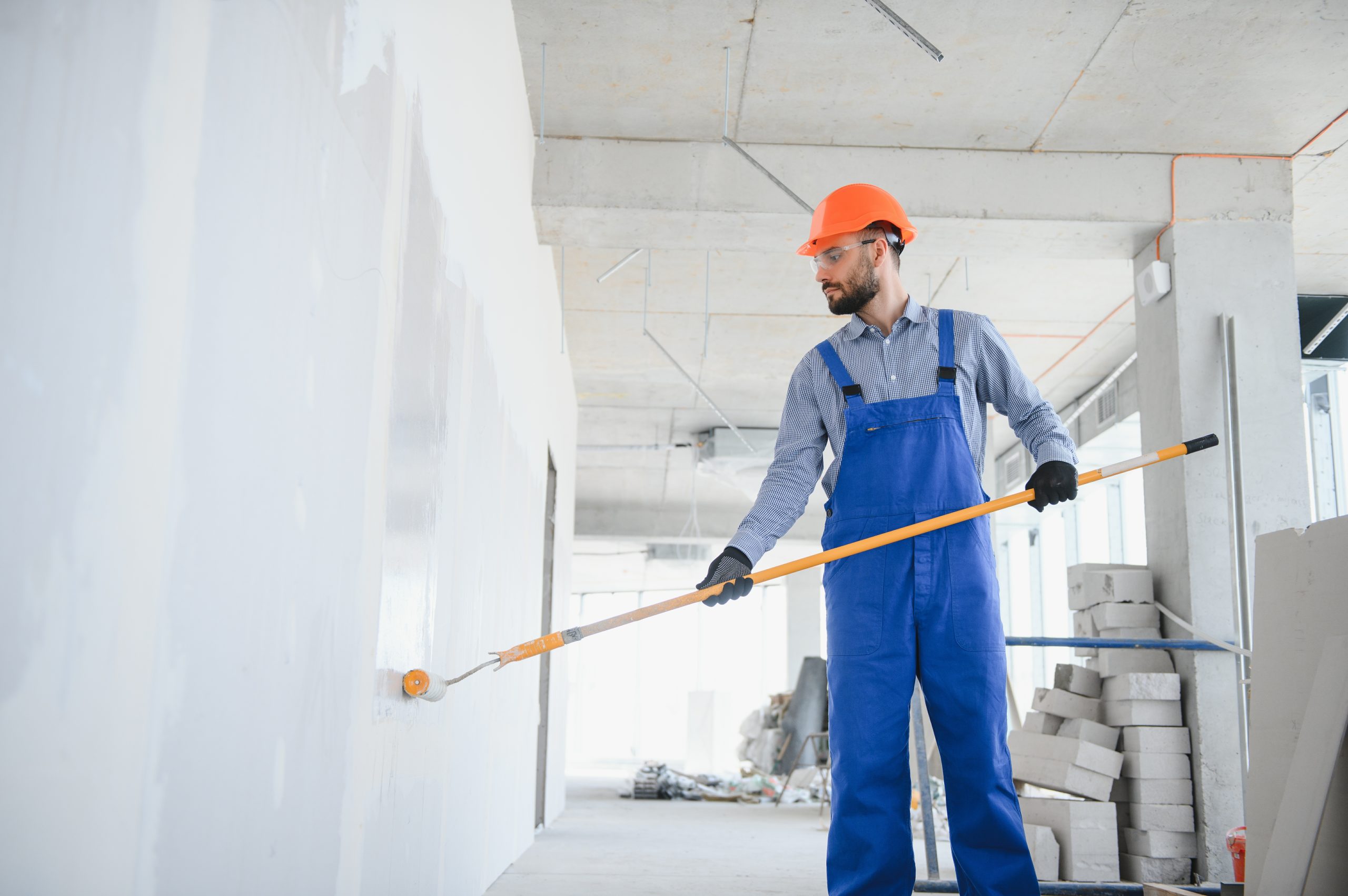 Painter in uniform paints the wall